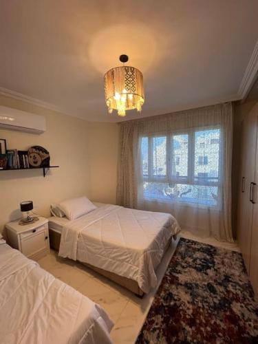 a bedroom with two beds and a chandelier at Charming apartment In Heliopolis in Cairo