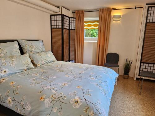 a bedroom with a bed with a blue bedspread with flowers at Alter Werkstatt in Jünkerath