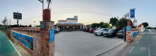 a parking lot with cars parked in front of a store at Hostal Cafeteria El Mero in Zahora