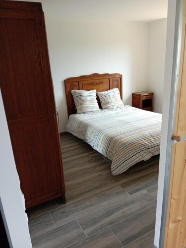 une chambre avec un lit avec une tête de lit en bois dans l'établissement Chez Tata Madeleine, à Montbras