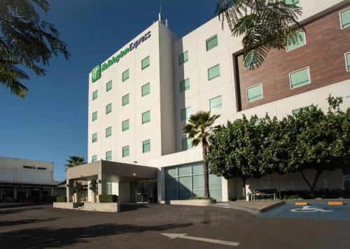 a hospital building with palm trees in front of it at Holiday Inn Express Guadalajara Iteso by IHG in Guadalajara