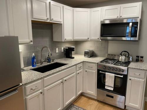 a kitchen with white cabinets and a stove and microwave at Walkable Allentown Downtown Gem with King Bed in Buffalo