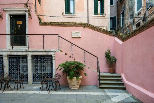 a pink building with stairs and tables and chairs at Palazzo dei Mori in Venice