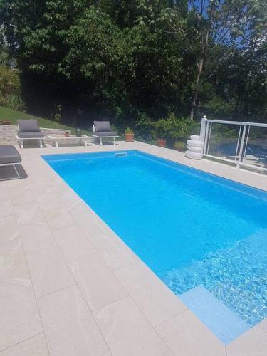 a large blue swimming pool with two chairs next to it at Green Garden in Roussel