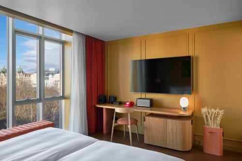 a hotel room with a bed and a desk with a tv at Verno House Budapest, Vignette Collection by IHG in Budapest