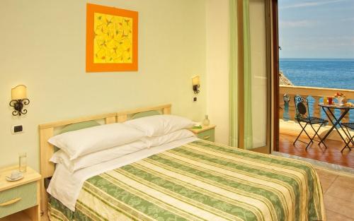 a bedroom with a bed with a view of the ocean at Jonic Hotel Mazzarò in Taormina