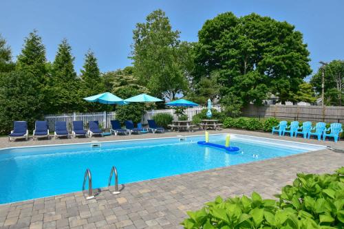 a swimming pool with blue chairs and umbrellas at Heated Pool AC 1 2 Mile to Beach in Harwich