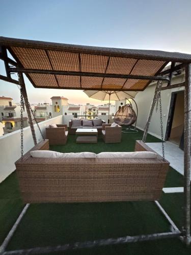 a patio with a swinging couch and chairs on a roof at Lasirena north coast Chalet With Roof , 3 rooms in Zāwiyat ‘Abd al Mun‘im