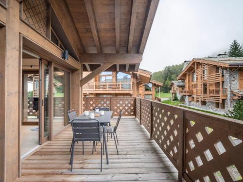une terrasse en bois avec une table et des chaises dessus dans l'établissement Appartement Neuf à Courchevel le Praz, 2 Chambres, Proche Pistes, Parking Inclus - FR-1-568-51, à Courchevel