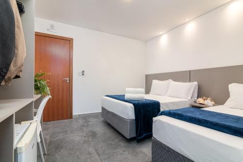 a hotel room with two beds with blue sheets at Hotel Conchas in Penha