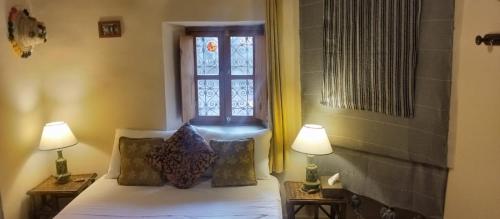 a bedroom with a bed with two lamps and a window at Les Jardins de Skoura in Skoura