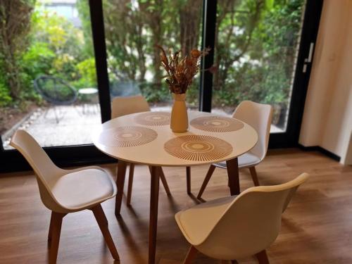 a table with chairs and a vase with flowers on it at Renovierte Doppelhaushälfte in bester Lage in Bottrop