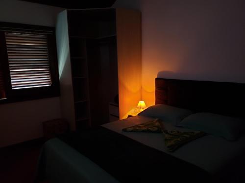 a dark bedroom with a bed and a lamp at Pousada Monte Sião in Sao Paulo