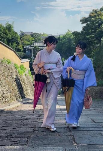 two women walking down a street holding umbrellas at Guesthouse RETURN in Kitsuki