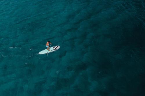 a person on a surfboard in the ocean at Bougainvillea 5102 Luxury Apartment - Reserva Conchal in Playa Conchal