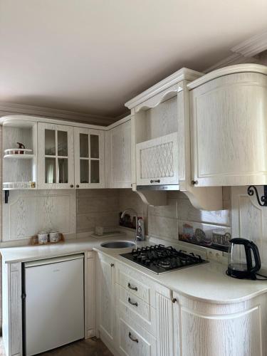 a white kitchen with white cabinets and a stove at Villa in Tsikhisdziri in Boboqvat'i