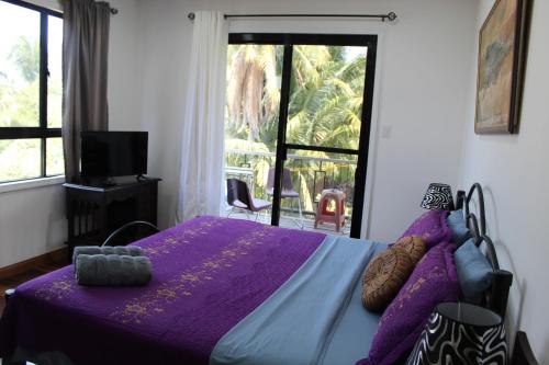 a bedroom with a purple bed and a window at CAJOMA Villa 1 in San Ignacio