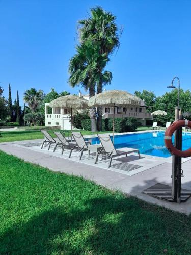 a row of lounge chairs next to a swimming pool at Leone Luxury Villas in Kalamaki