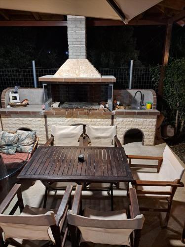 a wooden table and chairs with a fire place at Μονοκατοικία Kathrin in Nea Kalikratia