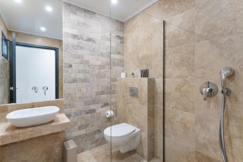 a bathroom with a shower and a toilet and a sink at Mon Avis Suites in Chrysi Ammoudia