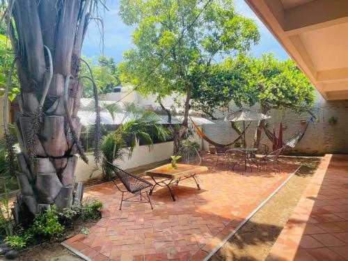 un patio con tavolo, sedie e un albero di Casa Sixta a 7min del aeropuerto internacional PMX y 2 cuadras terminal autob ADO a Puerto Escondido