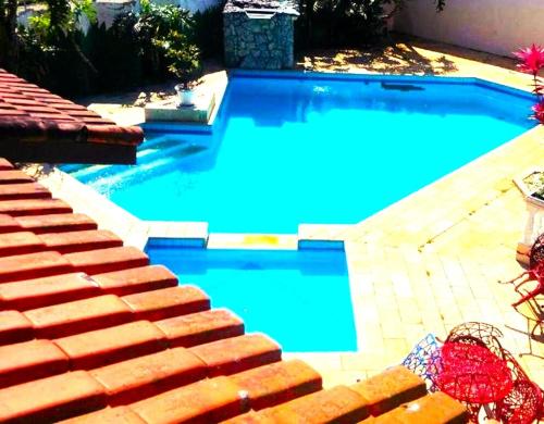 a swimming pool with blue water and some stairs at Pousada D'Ibiza - Itanhaém in Itanhaém