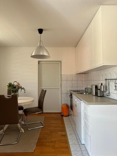 a kitchen with white cabinets and a table with chairs at Apartman Siesta in Kiseljak