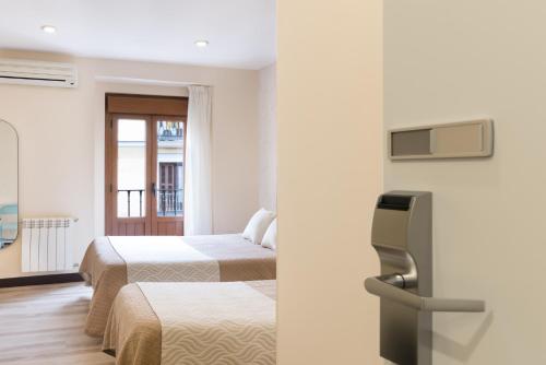 a hotel room with two beds and a tv at Hostal Art Madrid in Madrid