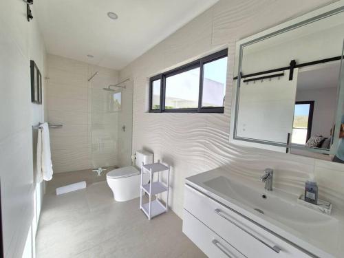 a white bathroom with a sink and a toilet at Casa Blanca Aruba in Saliña Cerca