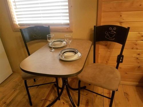 a table and chairs with plates and wine glasses at AC - #2 Bear Cabin in Ruidoso