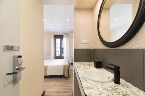 a bathroom with a sink and a mirror and a bed at Hostal Art Madrid in Madrid