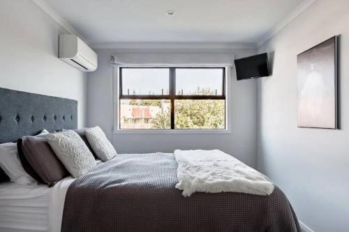 a bedroom with a large bed and a window at Contemporary Townhouse in Central Hamilton in Claudelands