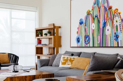 a living room with a gray couch and a painting at Modern Corner Apartment Seibal - Vidanta in Nuevo Vallarta 
