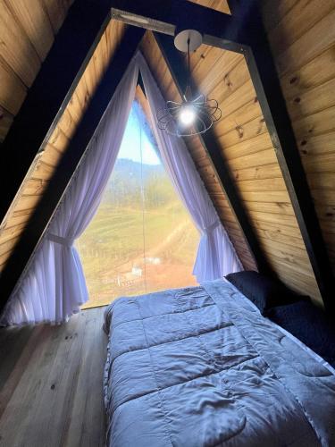 a bedroom with a large window in a attic at Chalé de Luxo em Paulo Lopes in Paulo Lopes