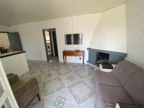 ein Wohnzimmer mit Couch und Kamin in der Unterkunft Casa Espaçosa e Confortável para Aluguel de Verão in Capão da Canoa