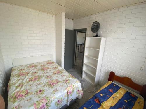 ein Schlafzimmer mit einem Bett und einem Bücherregal in der Unterkunft Casa Espaçosa e Confortável para Aluguel de Verão in Capão da Canoa