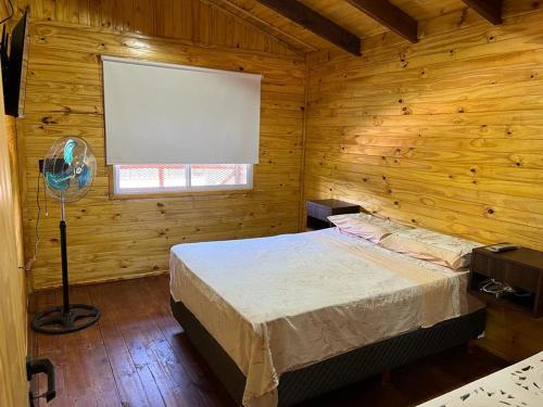 a bedroom with a bed in a wooden cabin at Don Gregorio in Empalme Lobos