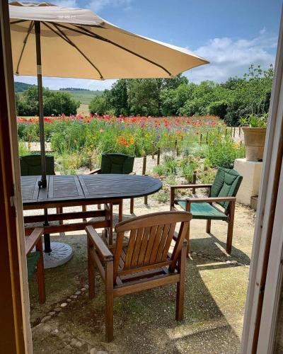 une table et des chaises avec un parasol et un champ de fleurs dans l'établissement The East Wing - Carcassonne, à Montréal