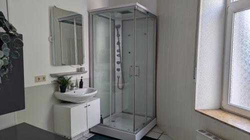 WilhelmshöheにあるGemütliche Wohnung mit Parkplatzのガラスのシャワーと洗面台を備えたバスルーム