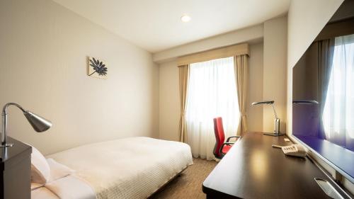 a bedroom with a bed and a desk with a television at JR-East Hotel Mets Fukushima in Fukushima