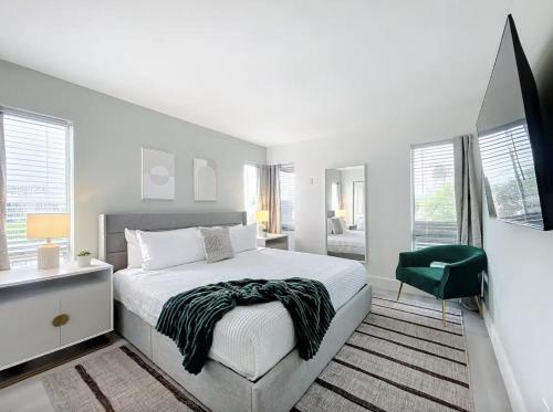 a white bedroom with a bed and a green chair at Cordova Arms By Rocketstay in Fort Lauderdale