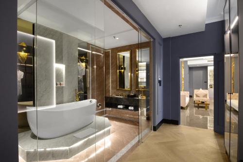 a bathroom with a tub and glass walls at The Granite Luxury Hotel Penang in George Town