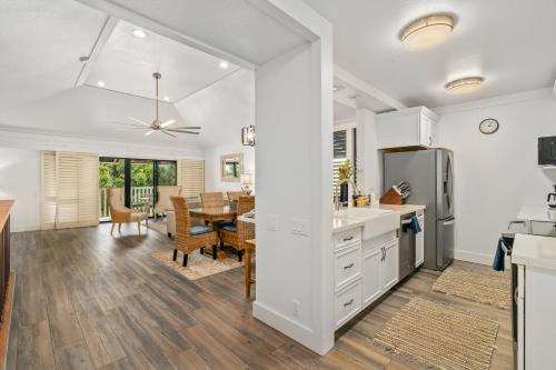 a kitchen and dining room with white cabinets and a table at Beautiful 2br condo with partial ocean view in Koloa