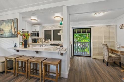 a kitchen with a sink and a counter with stools at Beautiful 2br condo with partial ocean view in Koloa