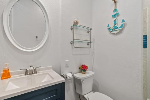 a bathroom with a sink and a toilet and a mirror at Beautiful 2br condo with partial ocean view in Koloa