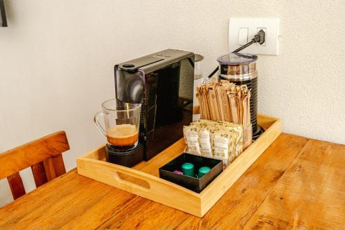 a coffee maker on a wooden table with a drink at JQY Beach Flats - 950m da Praia - Garagem subterrânea - Estação de carregamento para veículos elétricos in Juquei