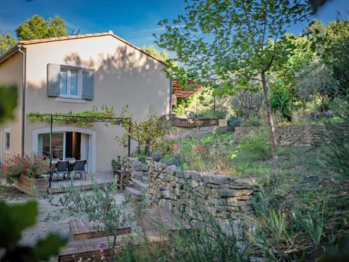 a house with a stone retaining wall and a garden at La Pinede in Faucon