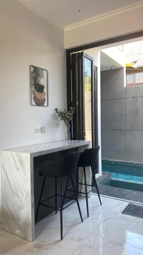 a kitchen with a counter and two black chairs at Pinasti Nirwana Villas in Batu