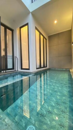a large swimming pool with a tile floor and windows at Pinasti Nirwana Villas in Batu