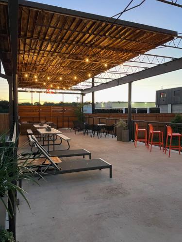 a patio with tables and chairs and a roof at Fyrebird Place - Industrial Loft with Pavilion & Yard in San Antonio